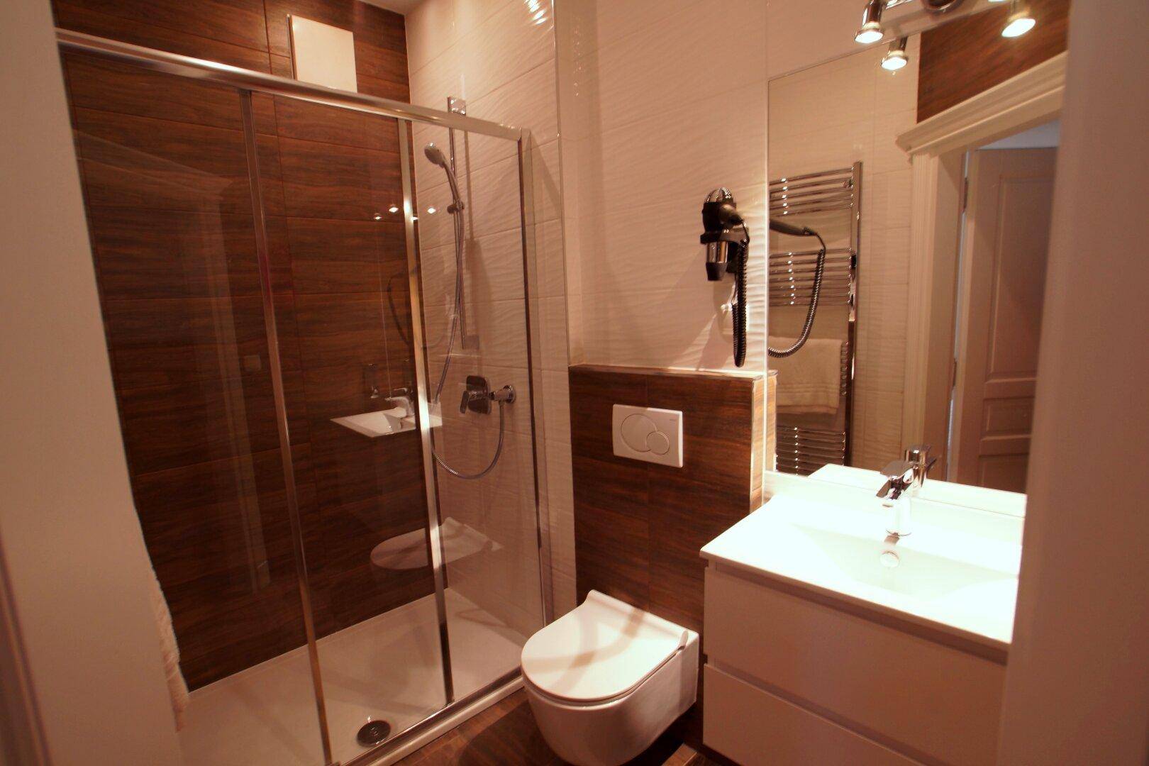 Helles Badezimmer mit Duschkabine, modernem Waschtisch und Holzoptik-Fliesen.