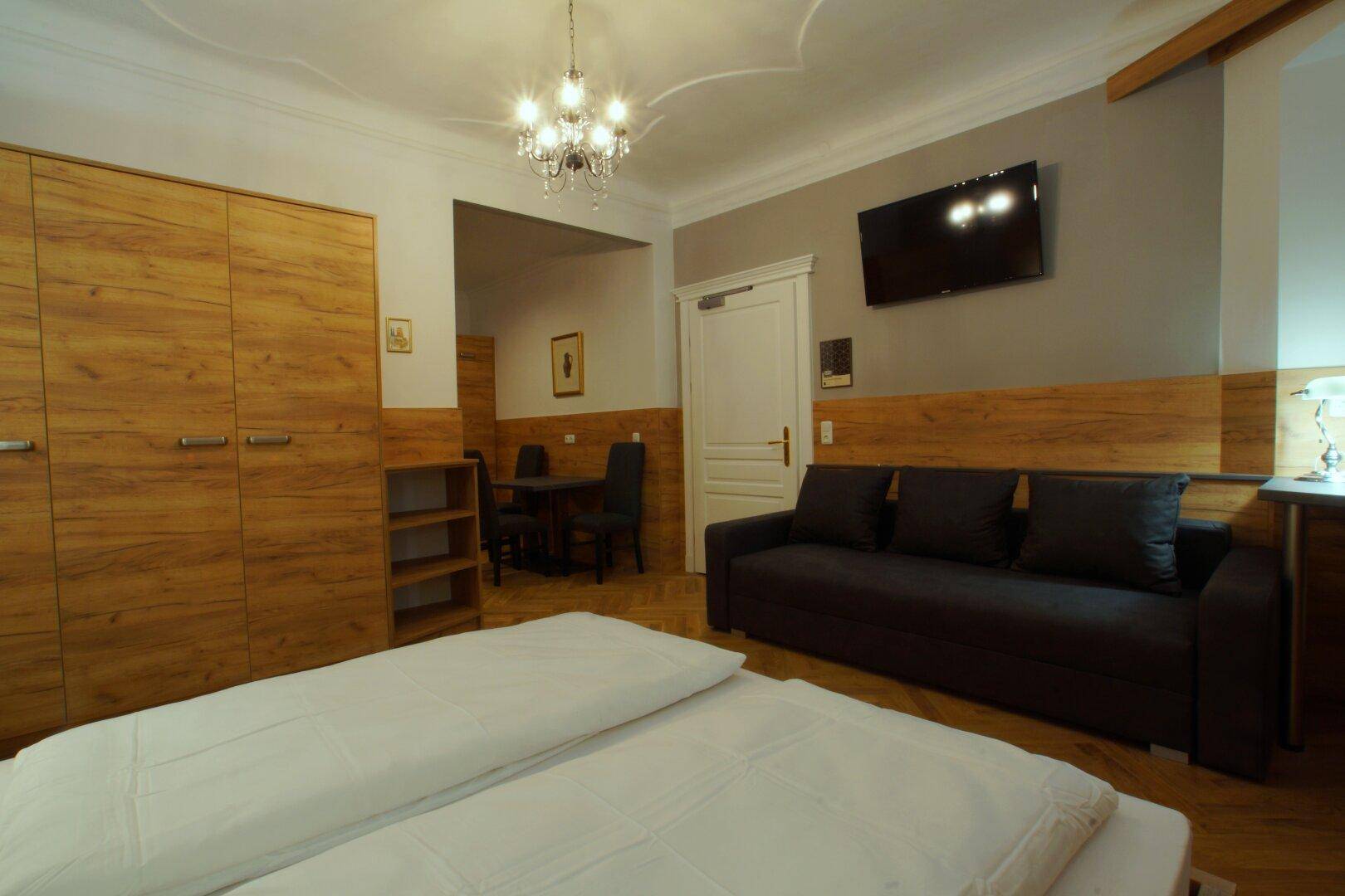 Offenes Studio-Apartment mit Schlafbereich, Sofa und Essbereich im Hintergrund.
