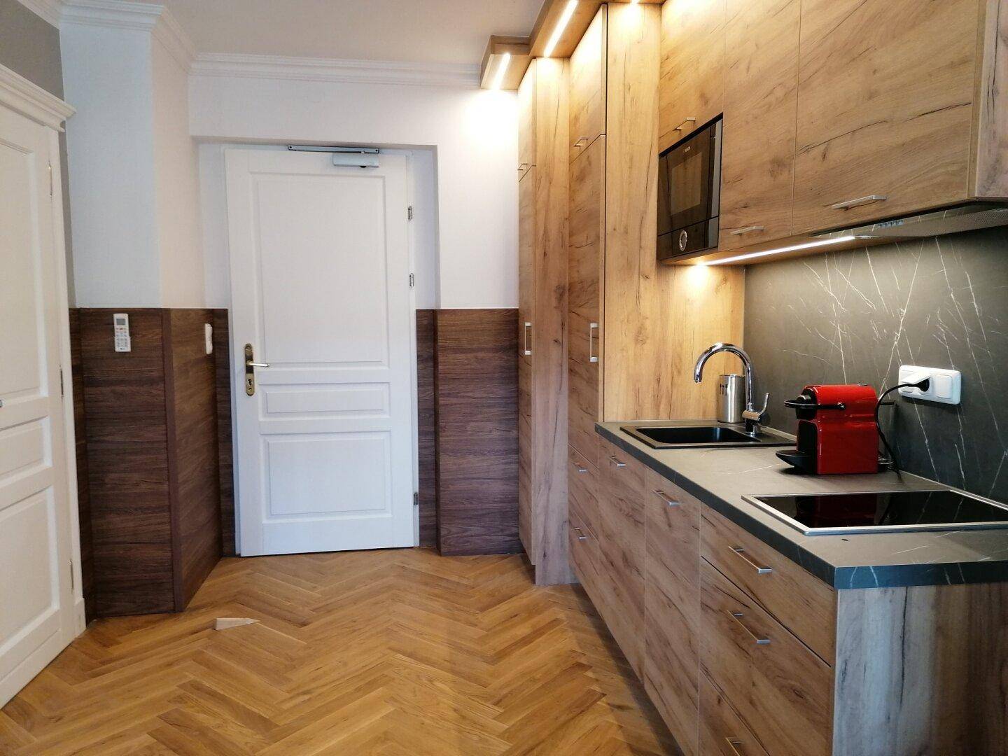 Moderne Küchenzeile mit Holzschränken, integrierten Geräten und Kaffeemaschine.