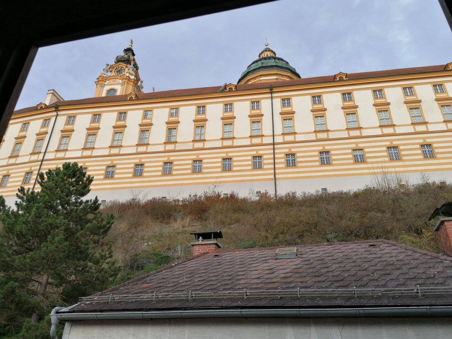 Historisches Gebäude mit gelber Fassade und Uhrturm, von unten fotografiert.