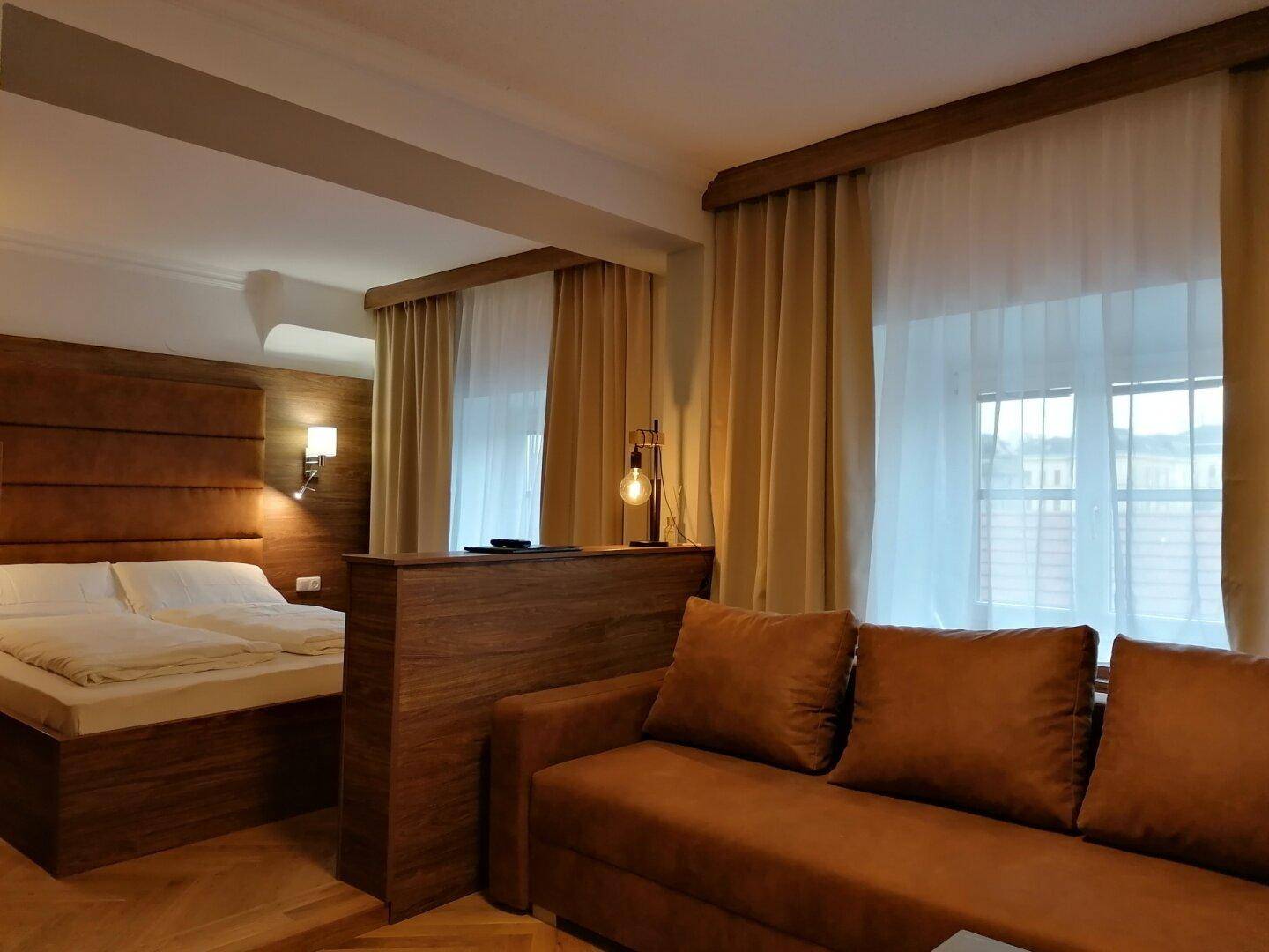 Offenes Studio-Apartment mit Schlafbereich, Sofa und Holzvertäfelung.