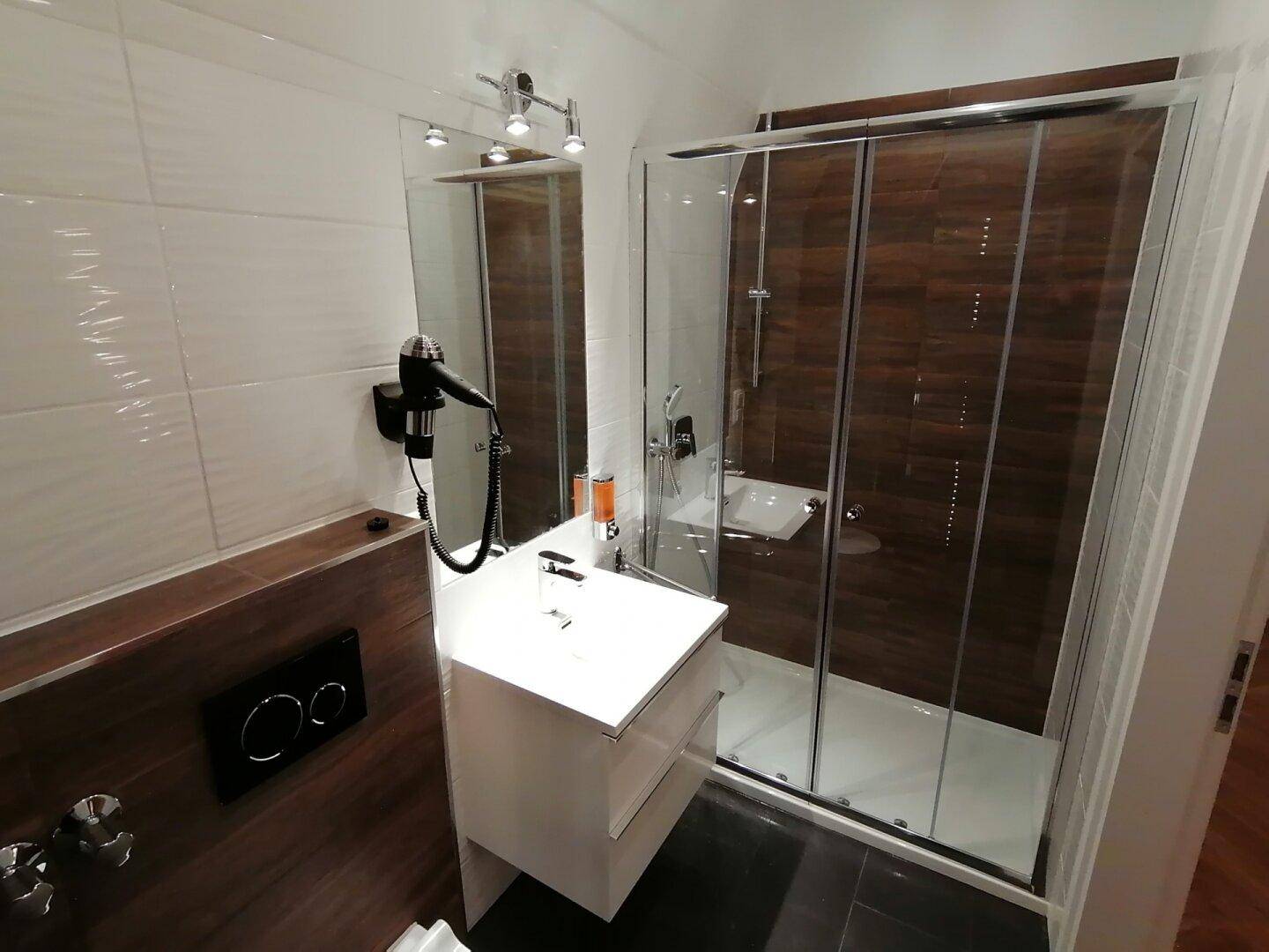 Modernes Badezimmer mit Duschkabine, Waschtisch und dunklem Fliesenboden.