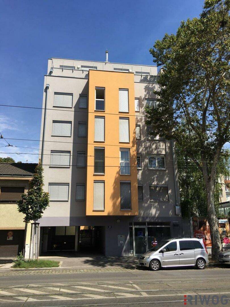 Modernes Mehrfamilienhaus mit farbiger Fassade und großen Fenstern an einer städtischen Straße.