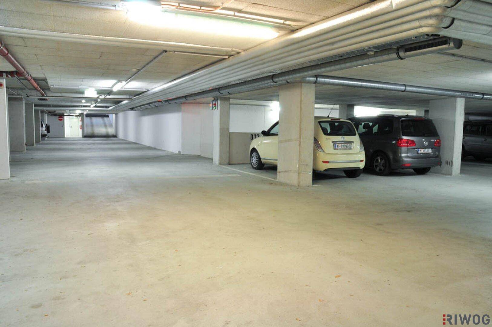 Geräumige Tiefgarage mit mehreren Stellplätzen und Betonboden, einige Fahrzeuge sind bereits geparkt.