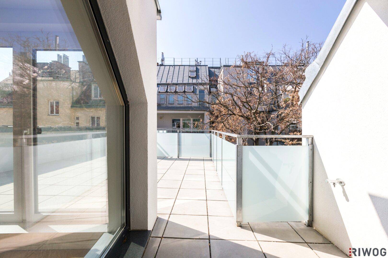 Helle Dachterrasse mit Zugang zum Innenbereich und Blick auf die umliegenden Gebäude.