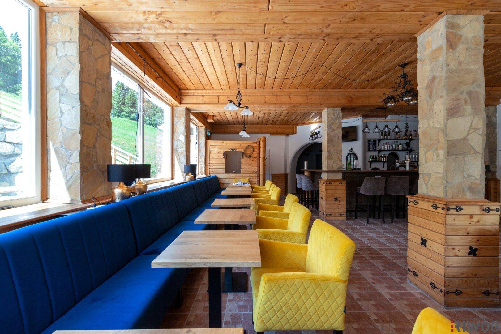 Geräumiger Essbereich mit Holzwänden, Steinpfeilern und einer langen blauen Sitzbank.