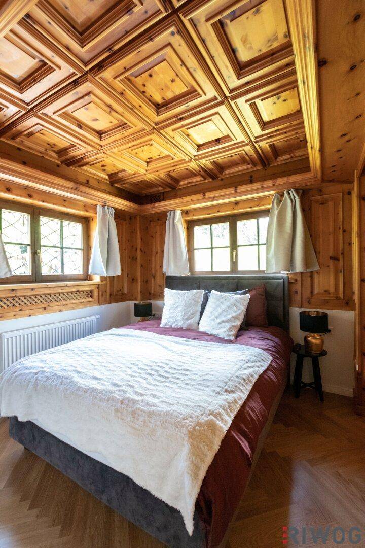 Helles Schlafzimmer mit Holztäfelung, Kassettendecke und einem bequemen Doppelbett.