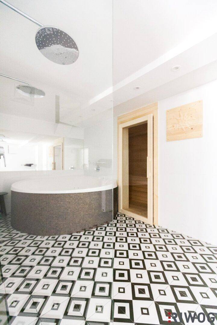 Modernes Badezimmer mit runder Badewanne, großer Dusche und auffälligen schwarz-weißen Fliesen.