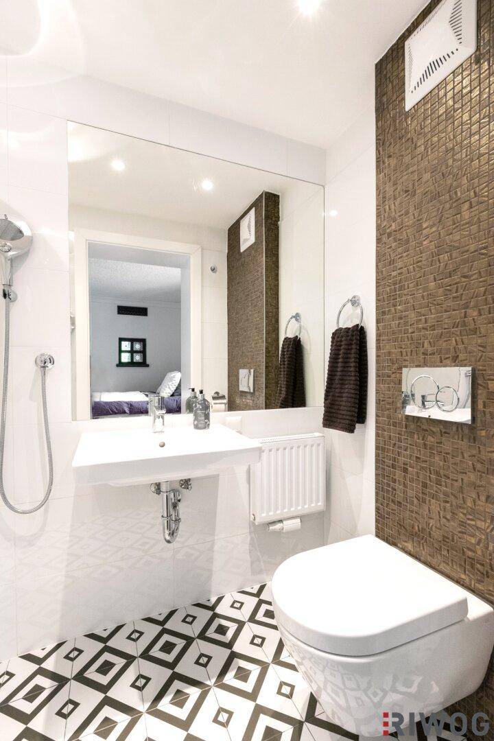 Modernes Badezimmer mit Wand-WC, Waschbecken und dekorativer brauner Fliesenwand.
