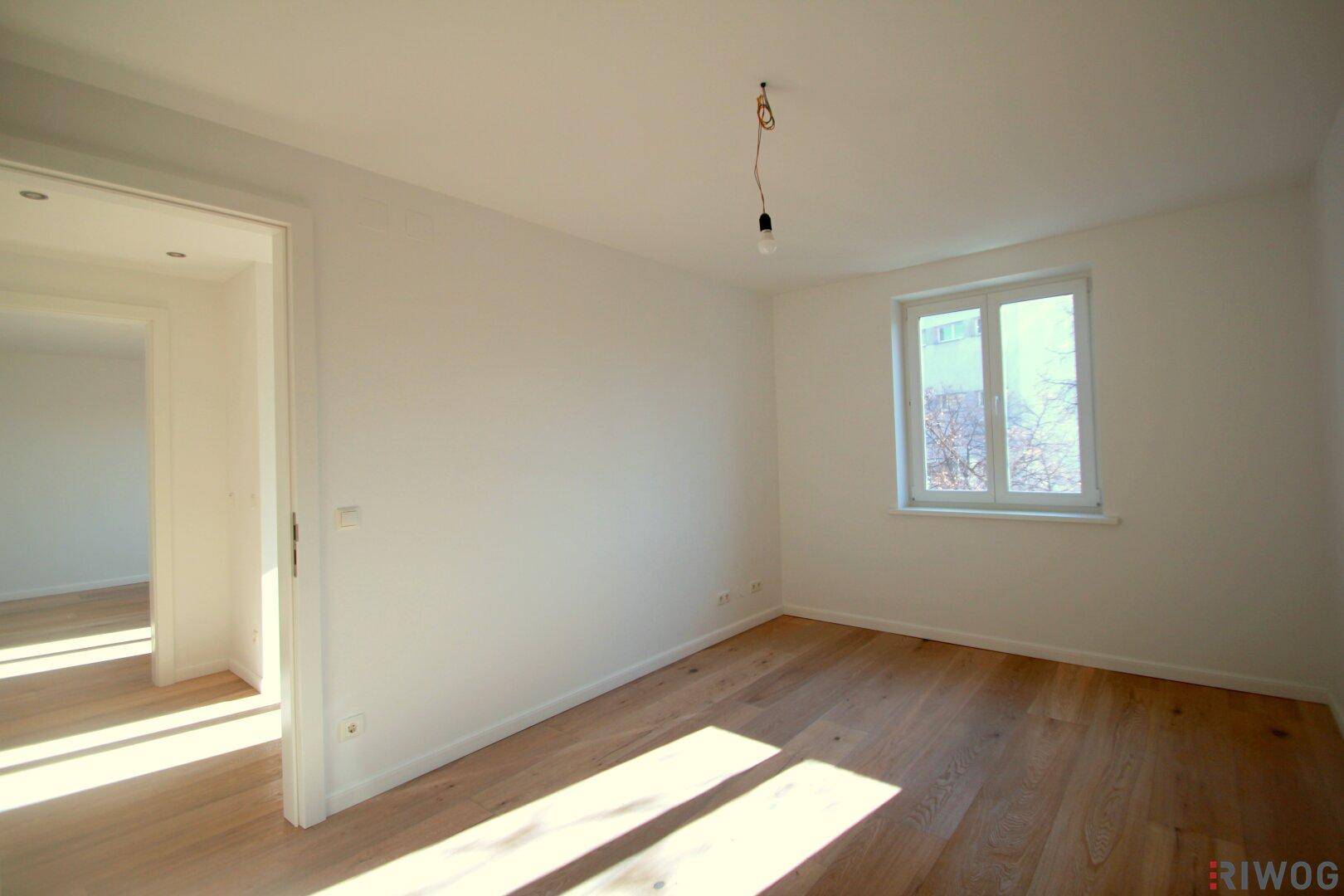 Freundliches Zimmer mit Holzboden und einem Fenster, das viel Tageslicht in den Raum bringt.
