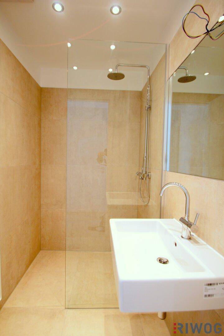 Modernes Badezimmer mit begehbarer Dusche, Einzelwaschbecken und beigefarbenen Fliesen.