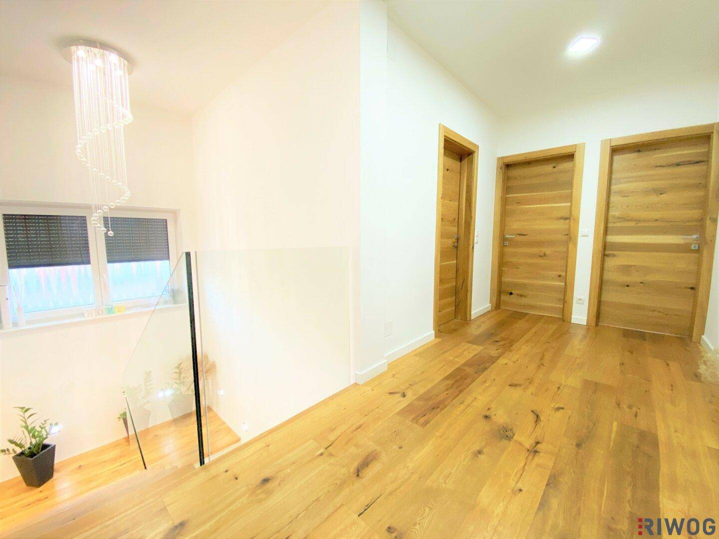 Heller Flur im Obergeschoss mit Holzboden, modernen Holztüren und Blick auf die Treppe.