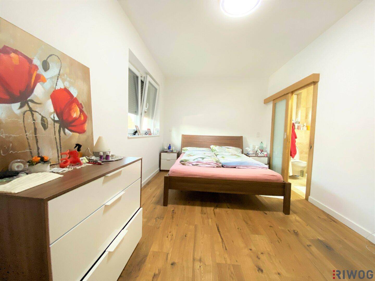 Gemütliches Schlafzimmer mit Holzboden, Doppelbett und Zugang zu einem eigenen Badezimmer.