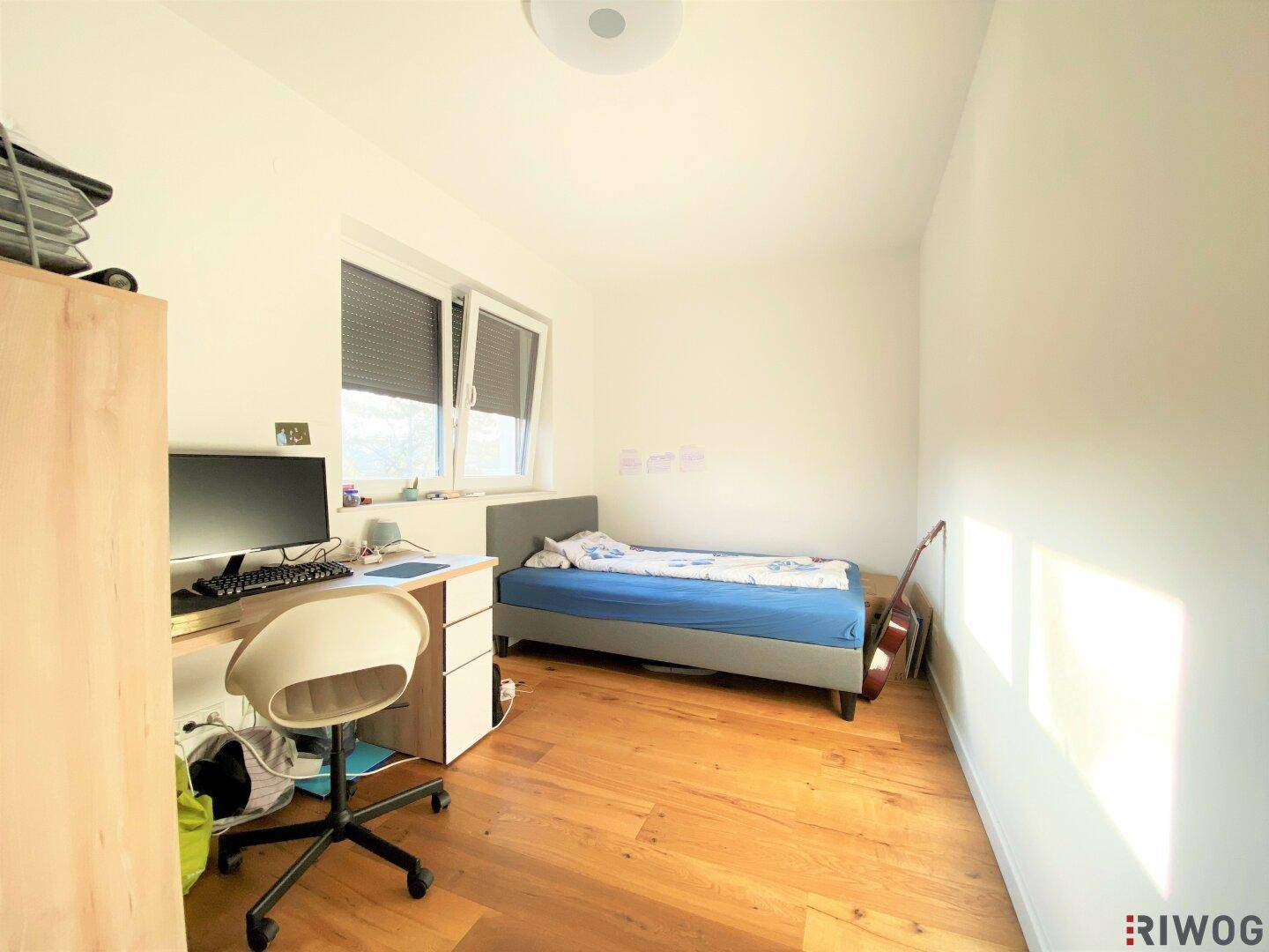Kinderzimmer mit Holzboden, Einzelbett, Schreibtisch und Fenster für natürliches Licht.