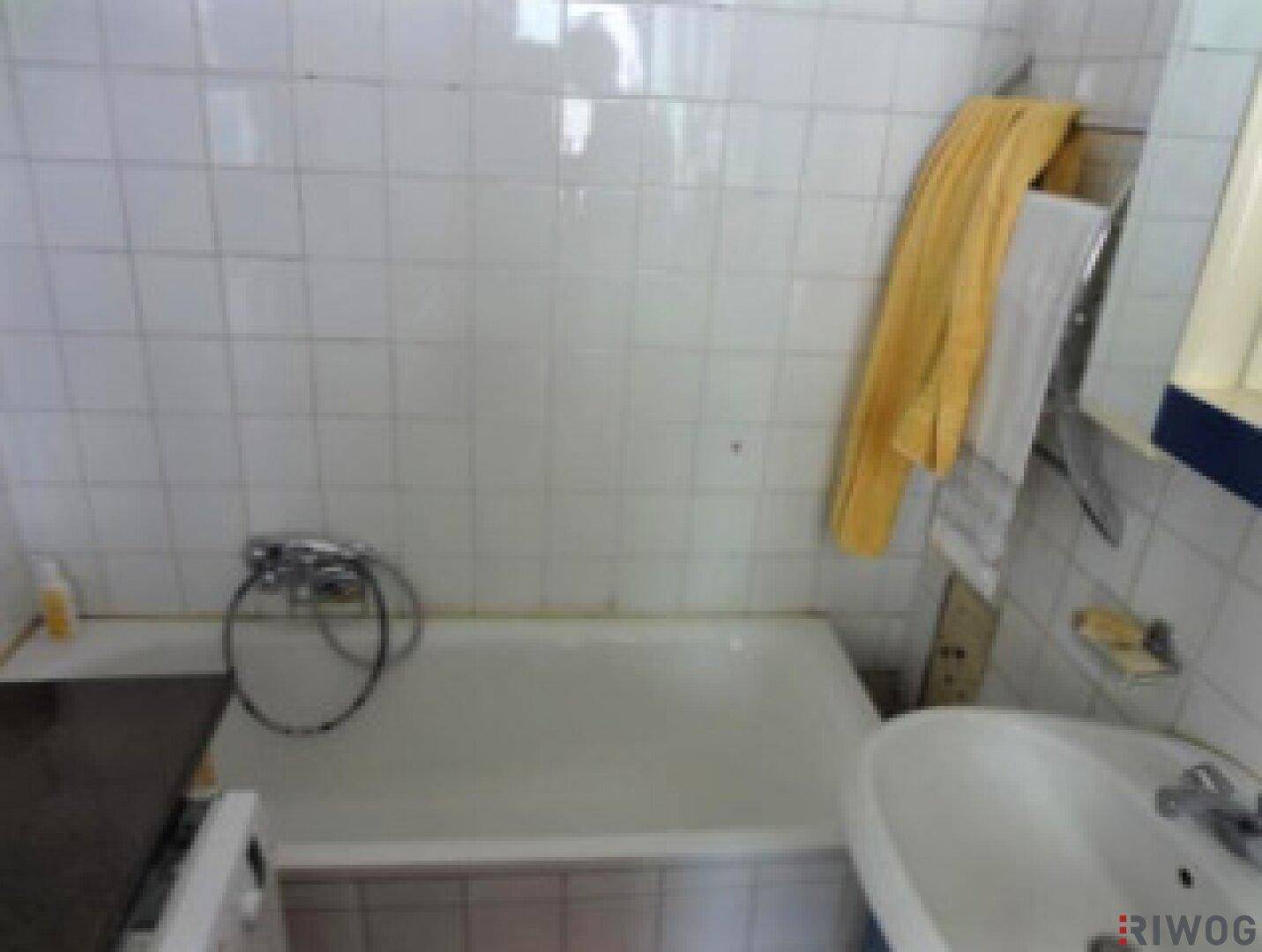 Badezimmer mit Badewanne, Waschbecken und weißen Fliesen an den Wänden.