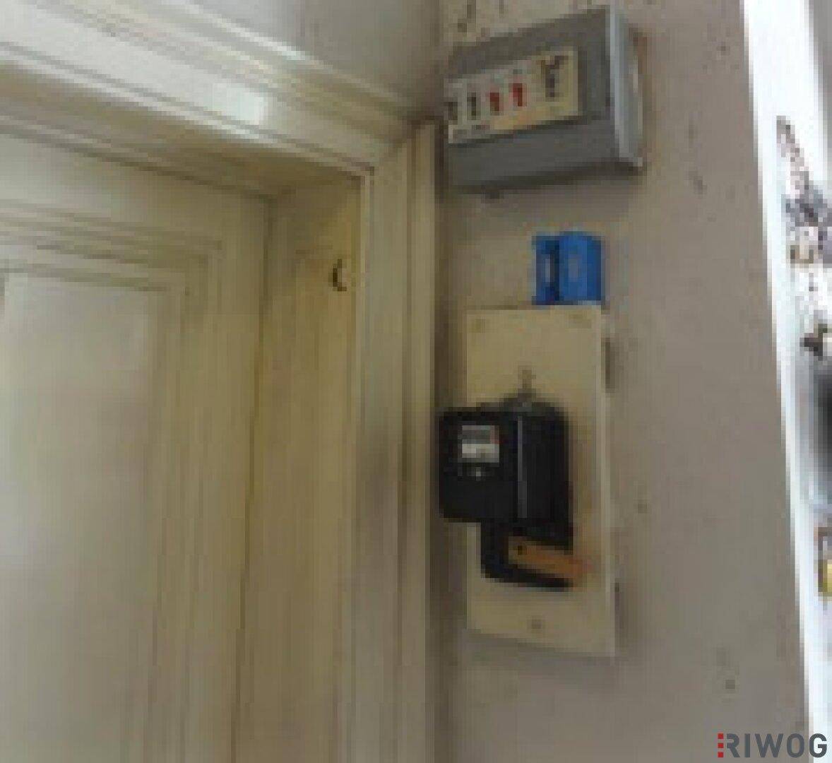 Elektrischer Sicherungskasten und Stromzähler an der Wand neben einer Tür.