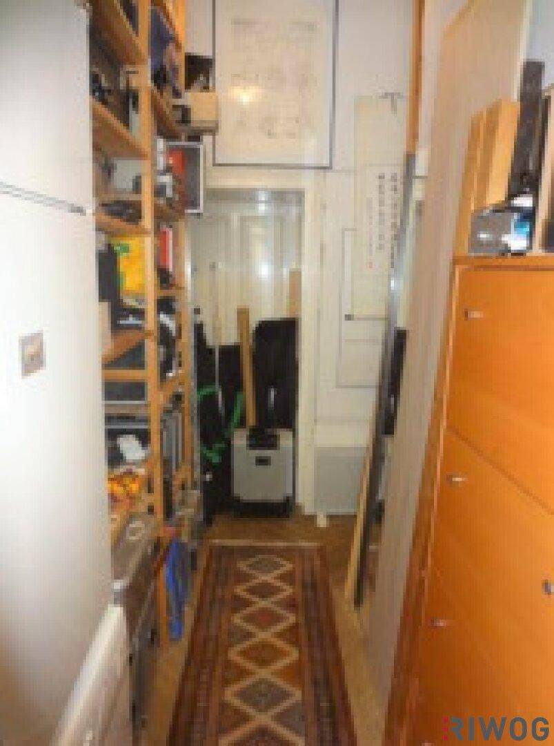 Schmaler Flur mit Regalen, Kühlschrank und Holzboden.