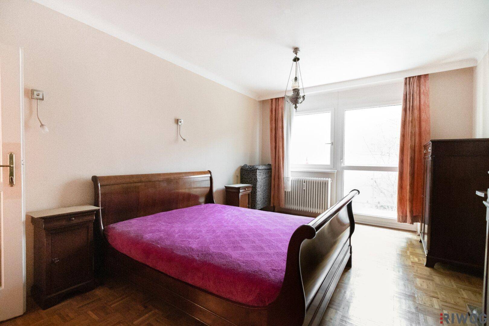 Schlafzimmer mit klassischem Holzdoppelbett, Nachttischen und großem Fenster.