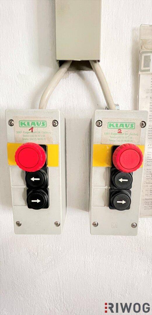 Detailansicht der Steuerungselemente für das mechanische Parksystem mit roten Not-Aus-Tasten an der Wand.