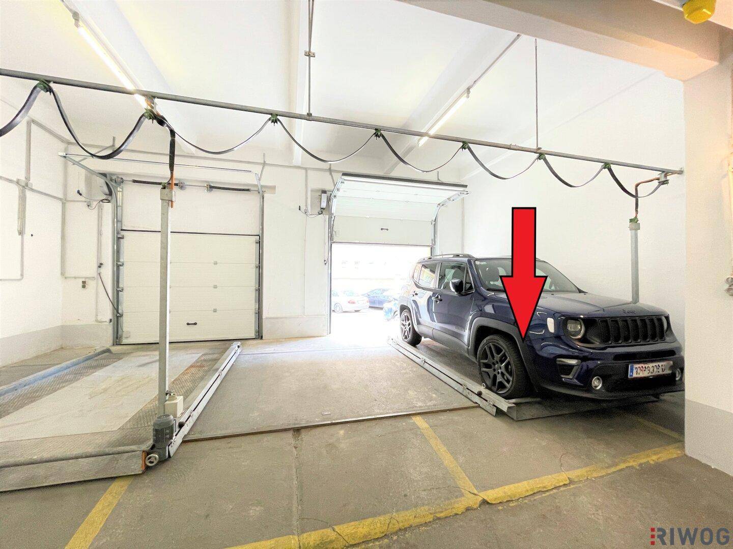 Tiefgarage mit einem Fahrzeug auf dem mechanischen Parksystem und einem freien Stellplatz daneben.