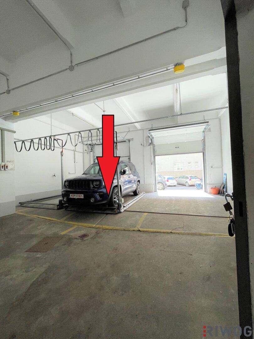 Weitwinkelansicht der Tiefgarage mit einem geparkten Auto auf dem mechanischen Parksystem und Rolltor.