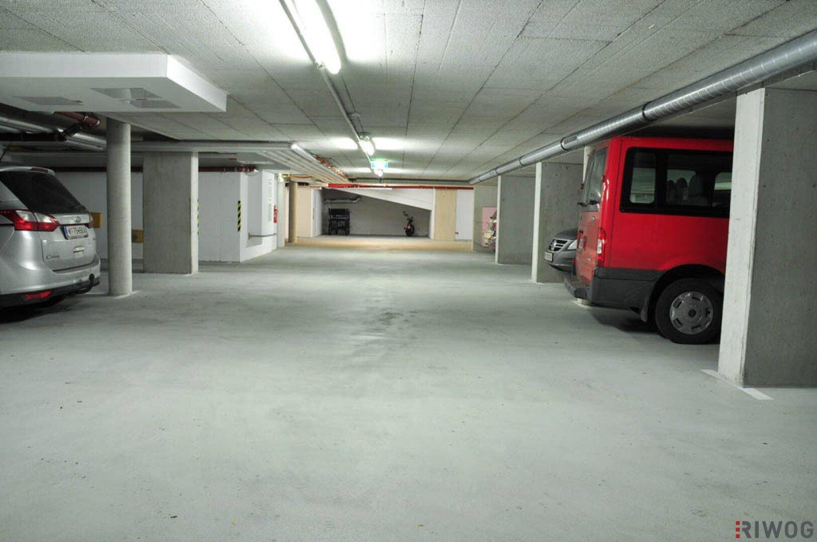 Geräumige Tiefgarage mit Betonstützen, Deckeninstallationen und ausreichend Platz für Fahrzeuge.