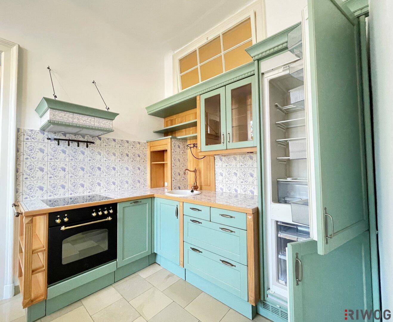 Traditionelle Küche mit mintgrünen Schränken, Holzarbeitsplatten und integriertem Kühlschrank.