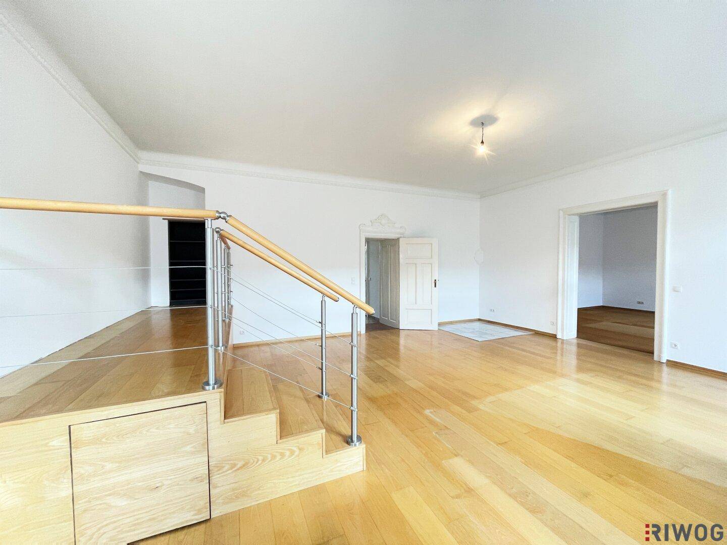 Blick auf den offenen Wohnbereich mit Holztreppe und Zugang zu weiteren Zimmern.