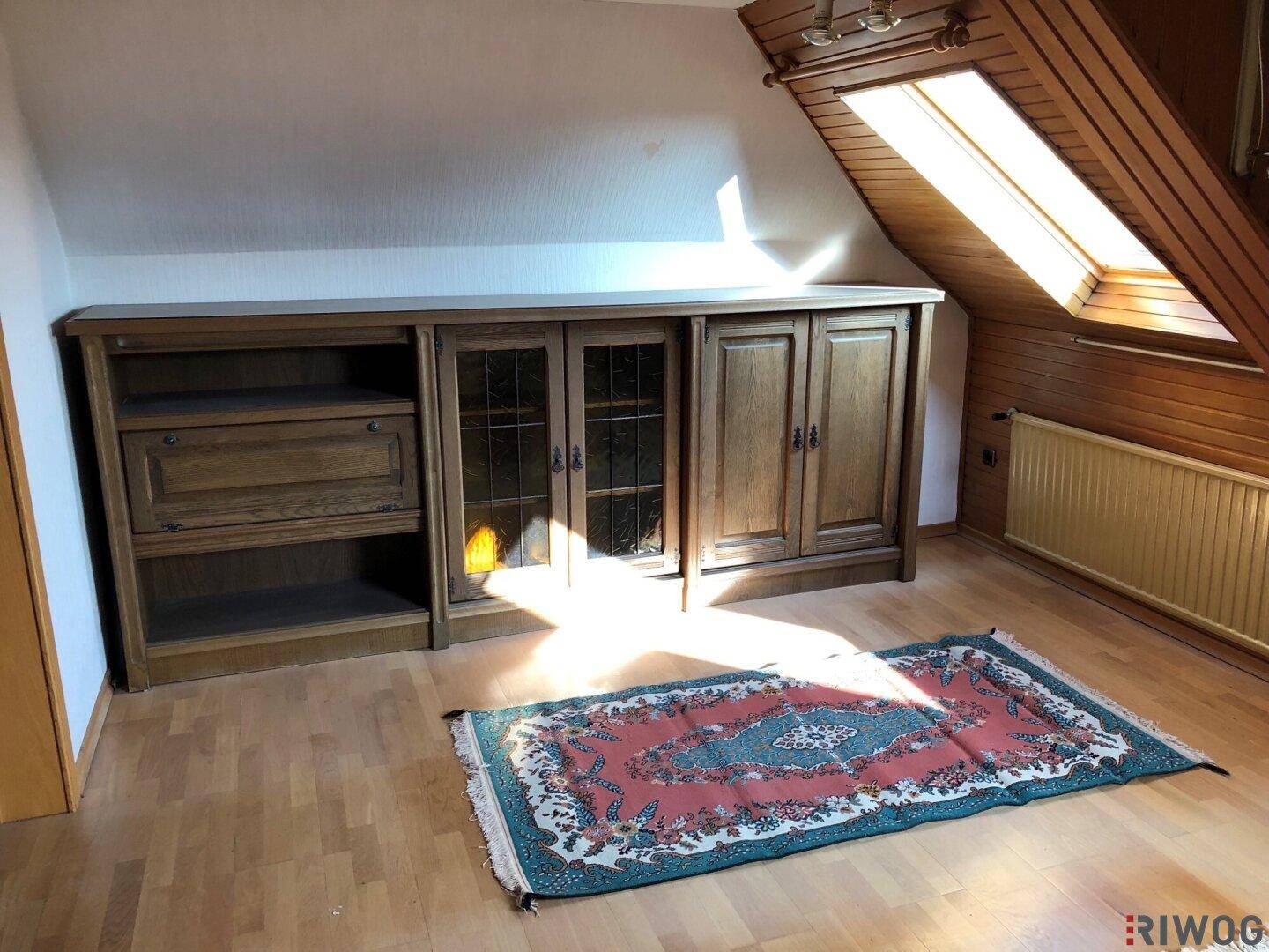 Dachgeschossraum mit Holzverkleidung, Dachfenster und einem Holzschrank.