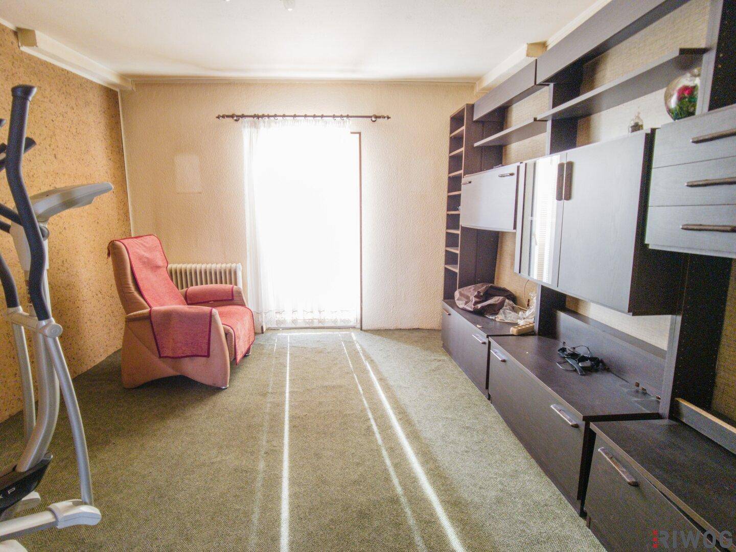 Helles Zimmer mit Teppichboden, großem Fenster und Wandregalen, ideal als Hobbyraum.