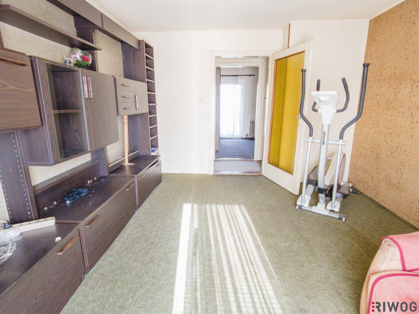 Geräumiges Zimmer mit Teppichboden und Wandregalen, das als Fitness- oder Hobbyraum genutzt werden kann.