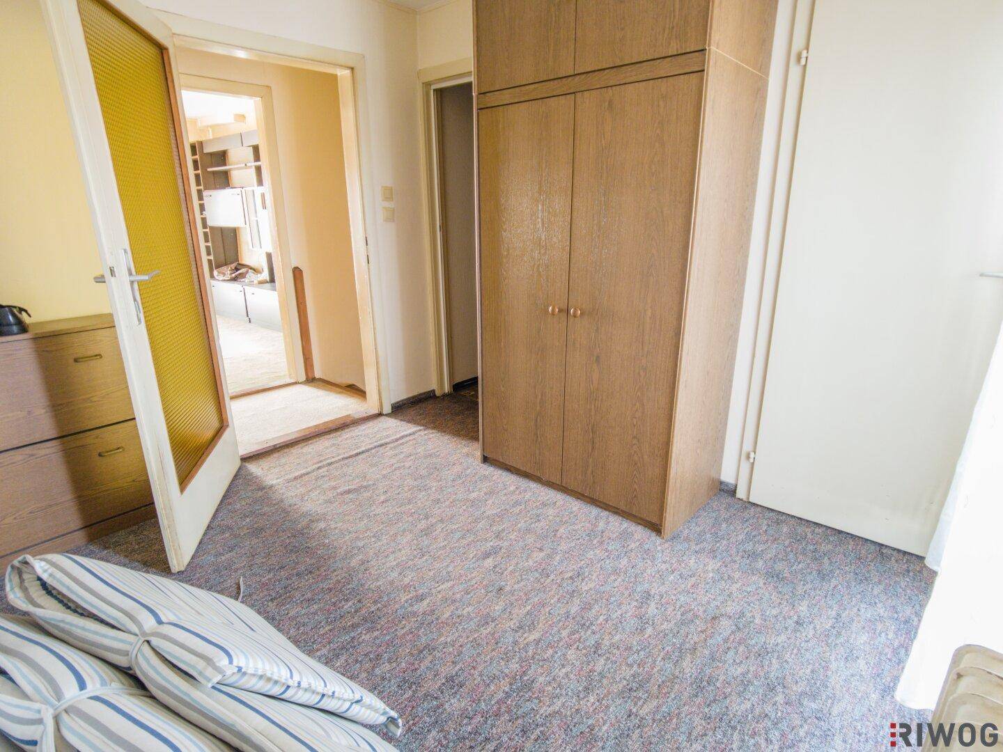 Schlafzimmer mit Teppichboden und Kleiderschrank, bietet Zugang zu weiteren Räumen.