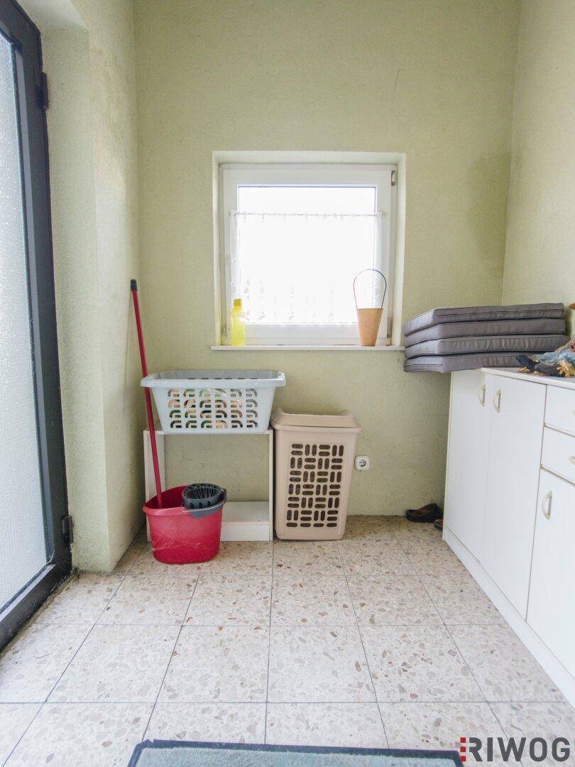Hauswirtschaftsraum mit Fliesenboden und Fenster, bietet Platz für Wäsche und Lagerung.