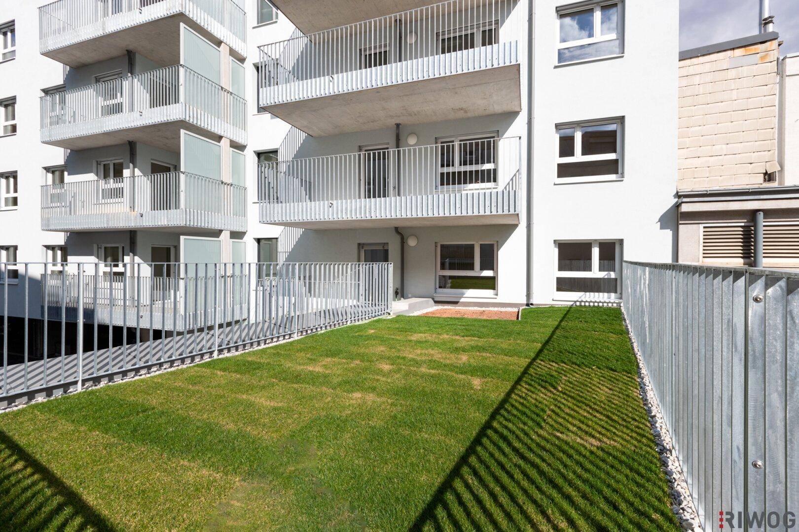 Gepflegte Rasenfläche im Gartenbereich eines modernen Wohnkomplexes mit Balkonen.