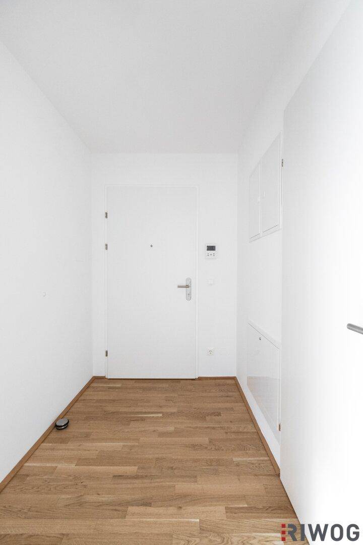 Heller Eingangsbereich mit Parkettboden und weißer Eingangstür, bietet einen freundlichen Empfang.