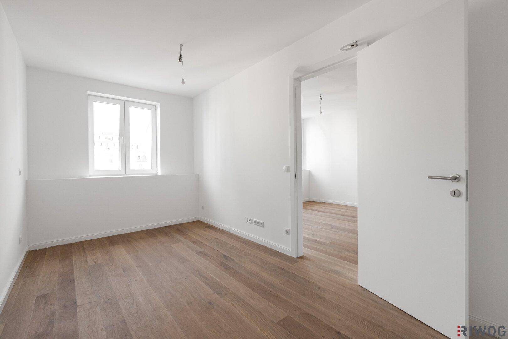 Freundliches Zimmer mit Parkettboden und Fenster, ideal als Schlaf- oder Arbeitszimmer nutzbar.
