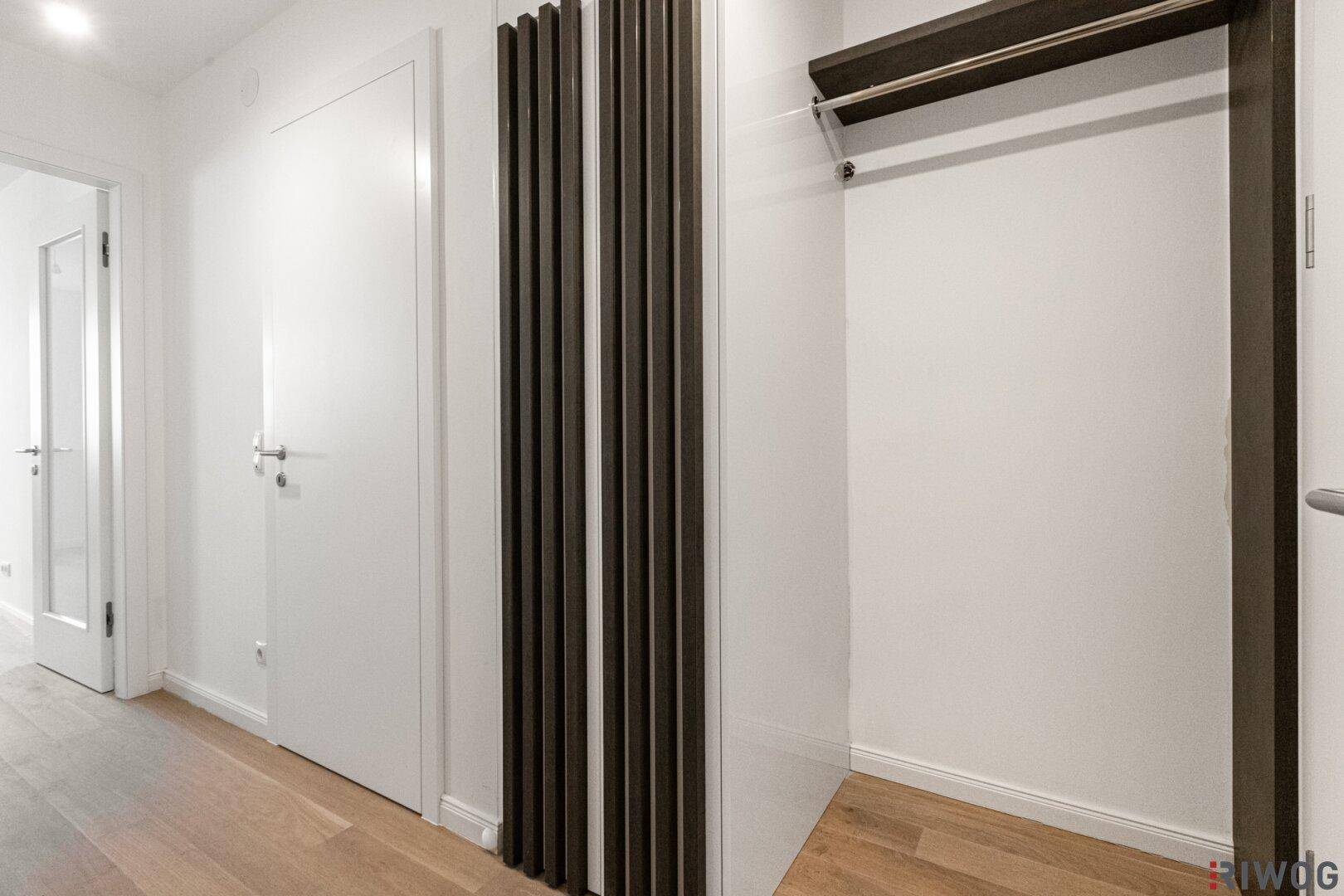 Heller Flur mit Holzparkett und praktischem, offenem Einbauschrank für Garderobe.