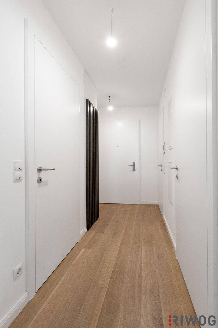 Langer, heller Flur mit Holzboden und mehreren Türen, der zu den Zimmern führt.
