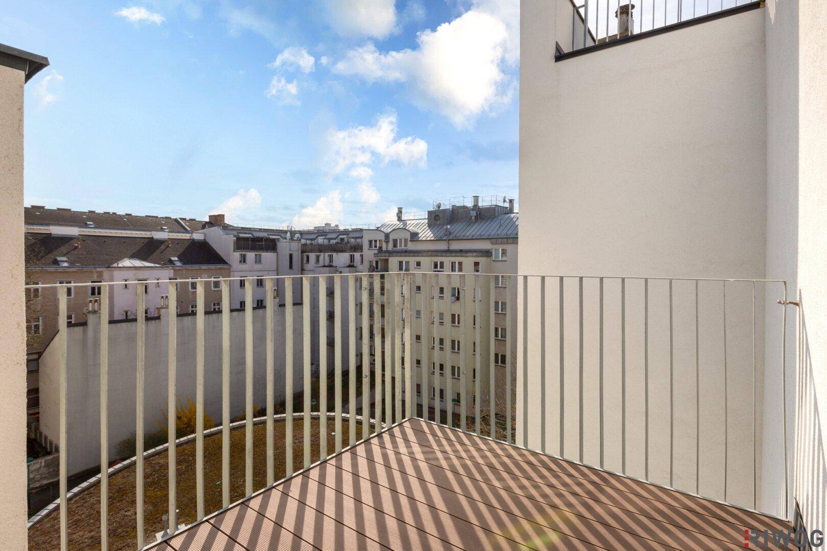 Moderner Balkon mit Holzboden und weitem Blick über die Stadt und die umliegenden Gebäude.