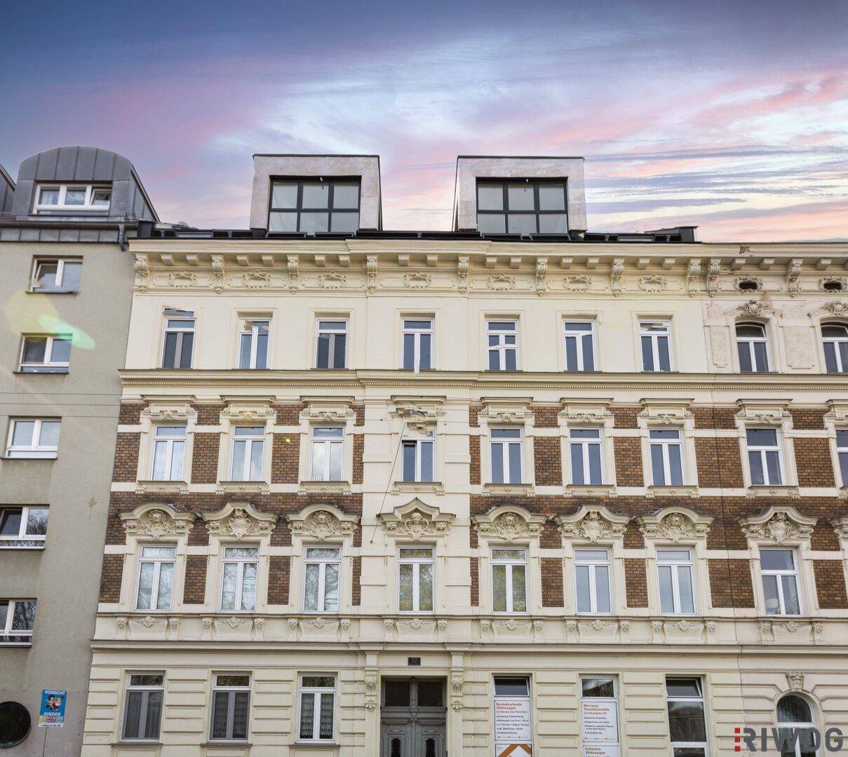 Historische Fassade eines Altbaus mit aufgesetzten modernen Dachgeschosswohnungen.