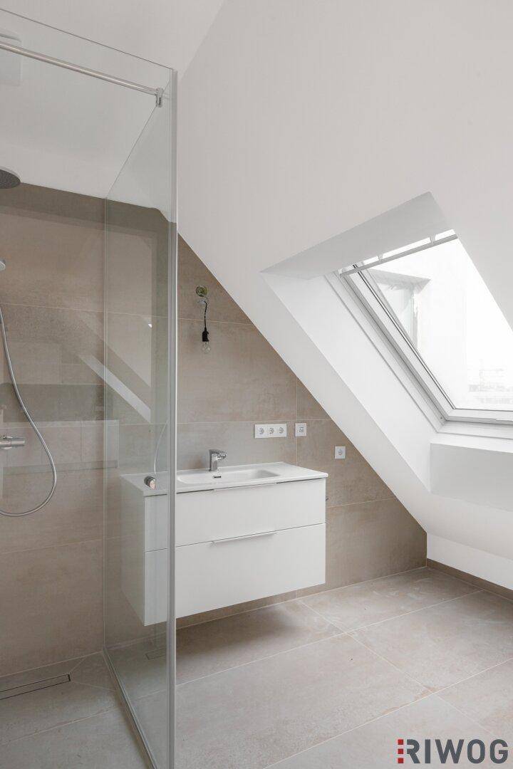 Modernes Badezimmer im Dachgeschoss mit begehbarer Dusche, Waschtisch und Dachfenster.