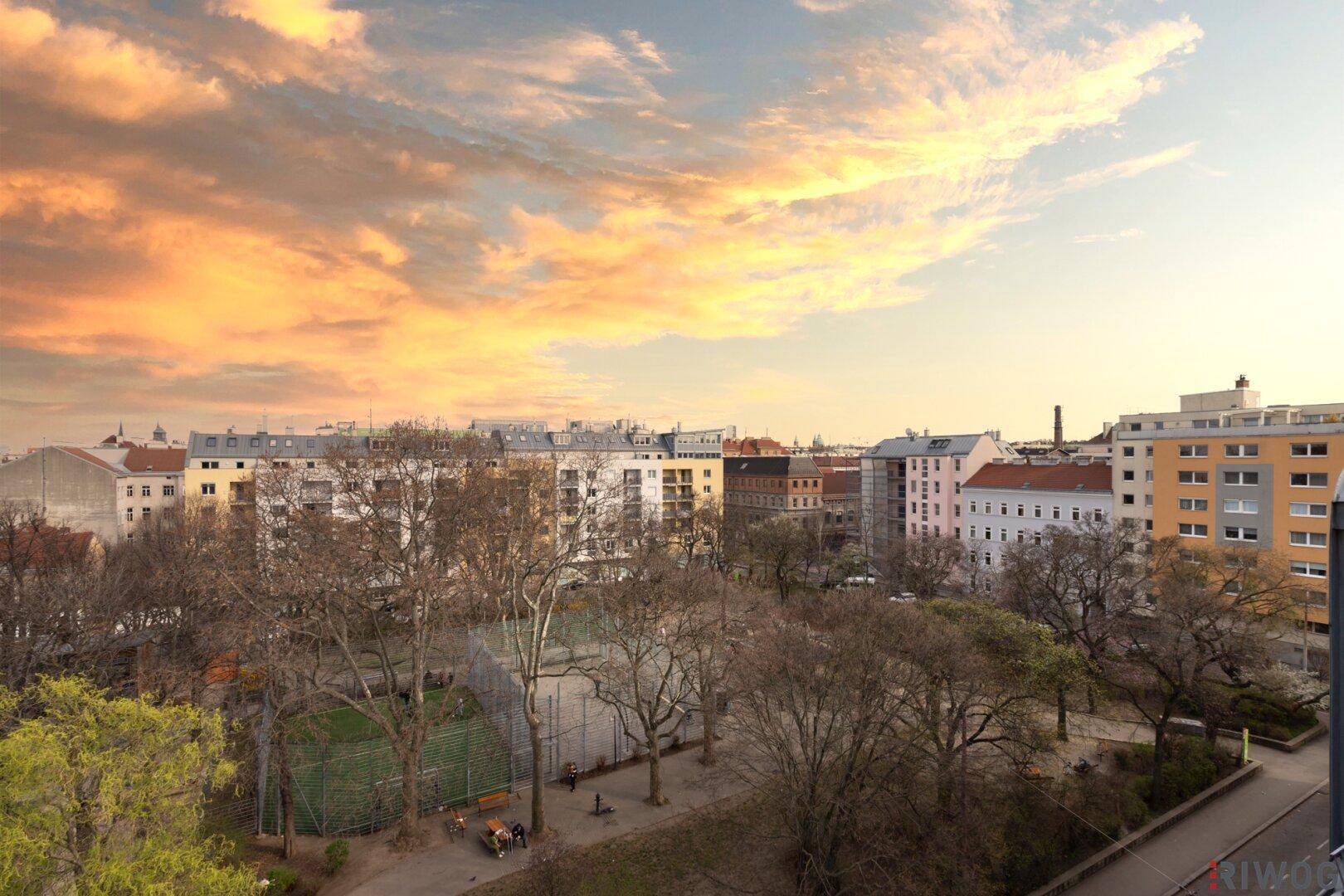 Panoramablick über die Stadt und einen grünen Park bei Sonnenuntergang.