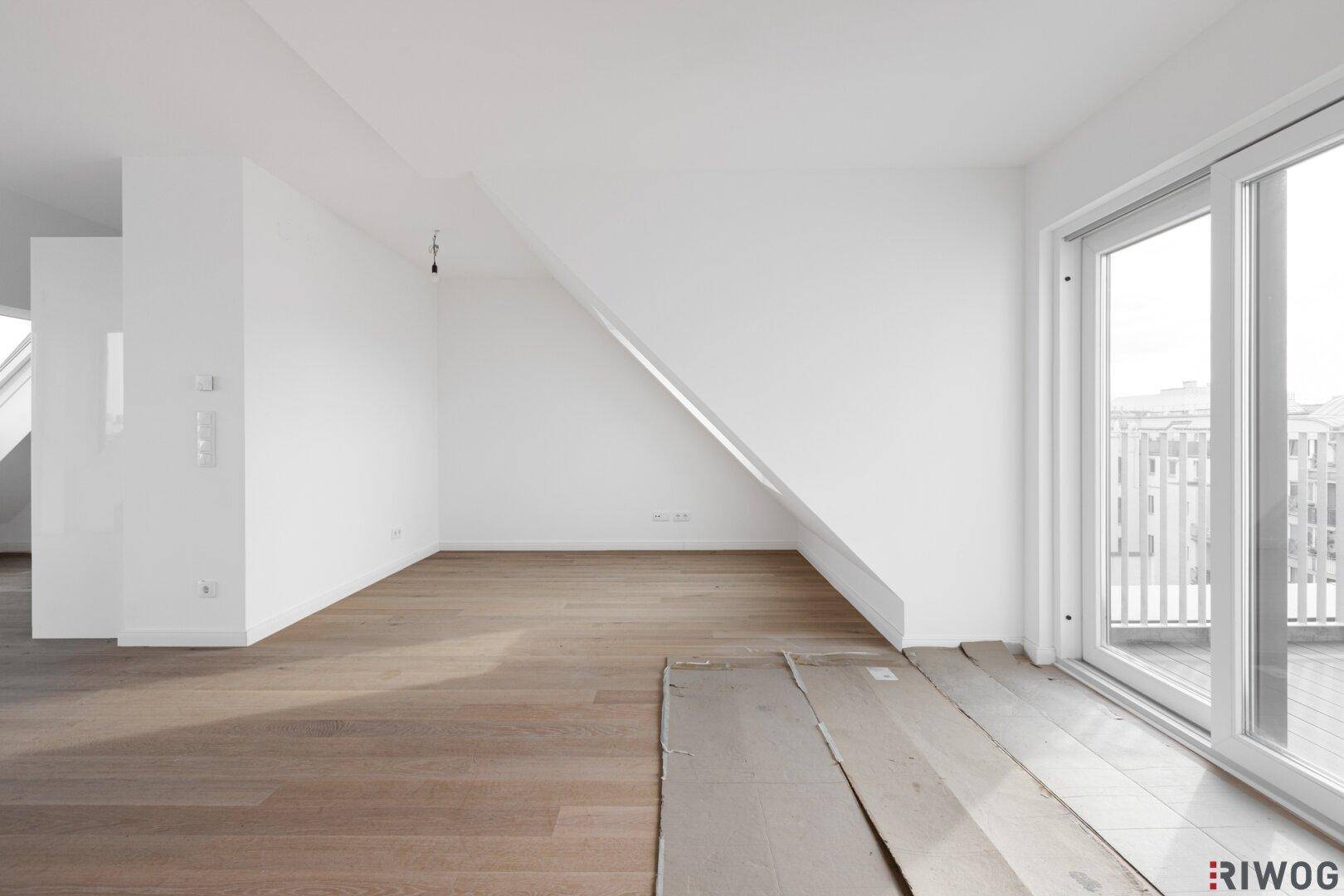 Geräumiger Dachgeschossraum mit Holzboden und Schiebetür zur Dachterrasse.