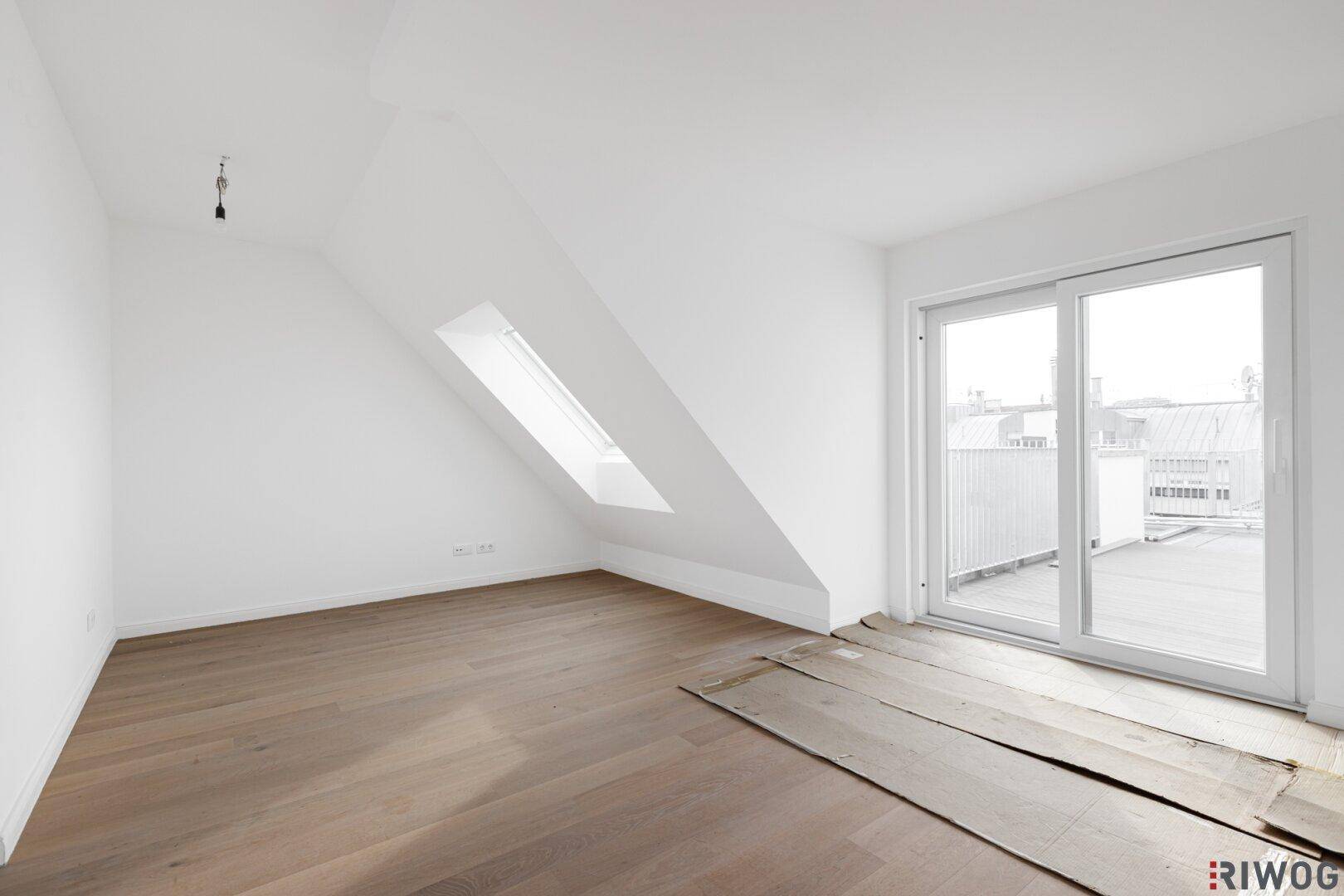 Heller Dachgeschossraum mit Holzboden und Zugang zu einer Dachterrasse.