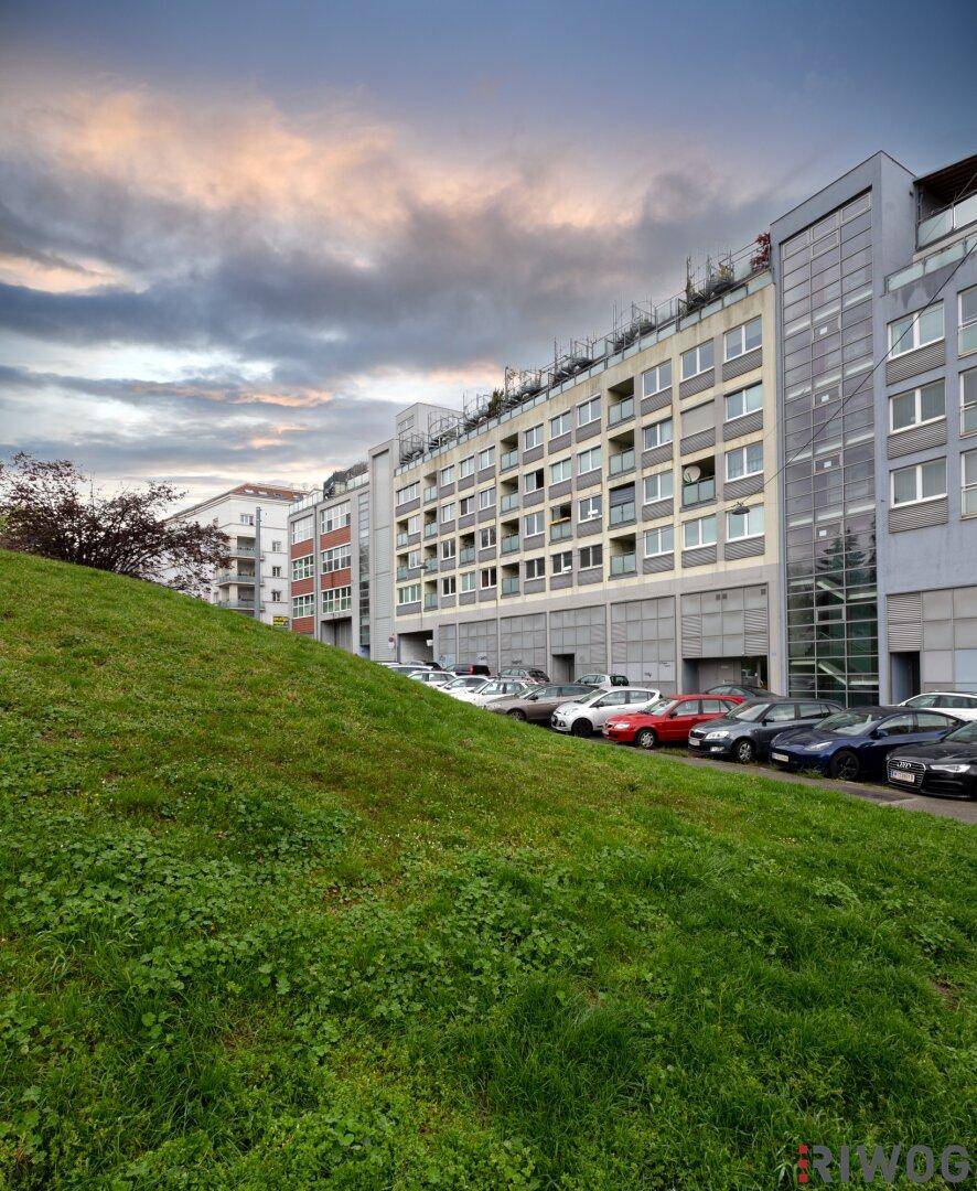 Mehrfamilienhaus mit Parkplätzen und Grünfläche in urbaner Umgebung.