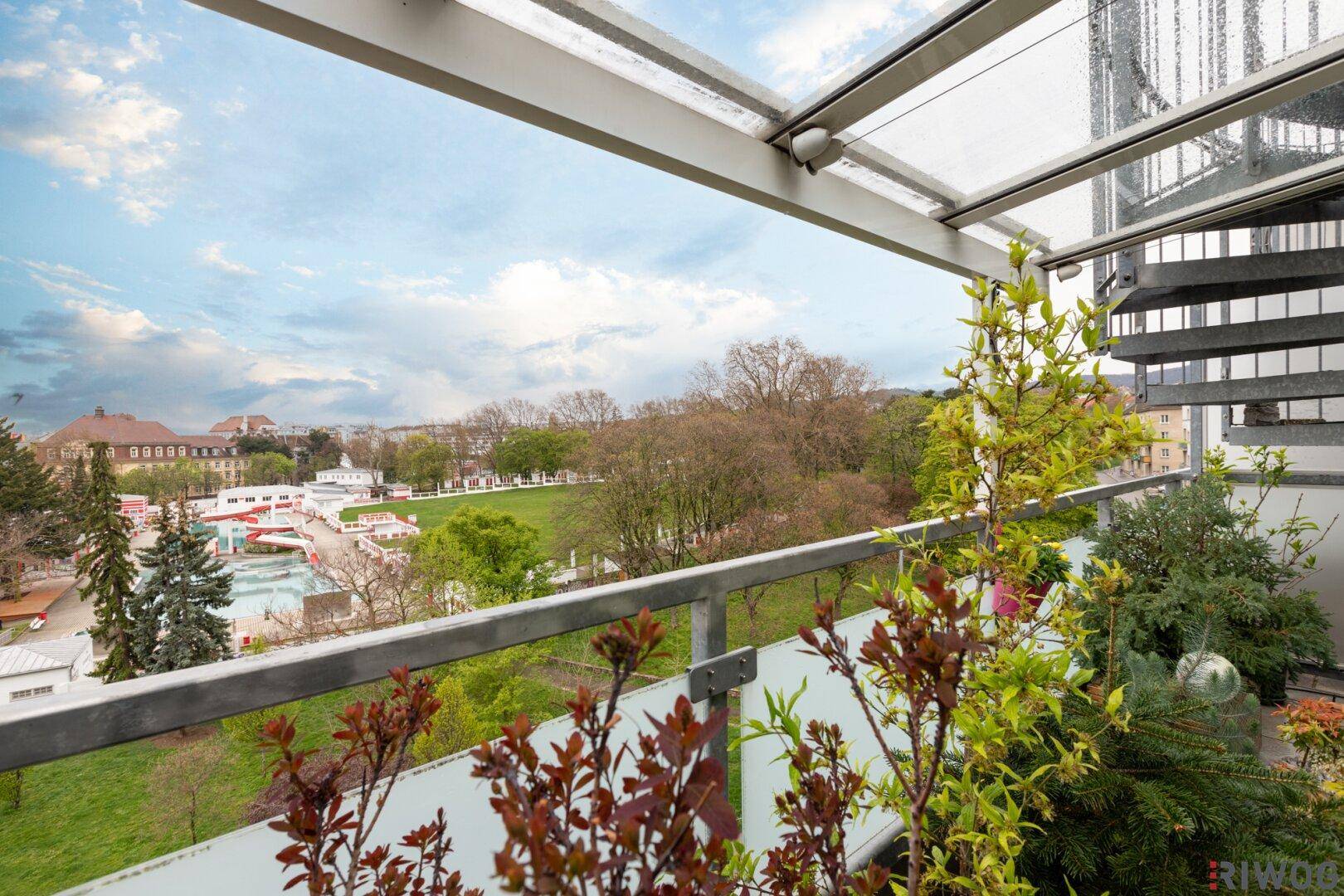 Begrünter Balkon mit Glasüberdachung und weitem Blick über die Umgebung.
