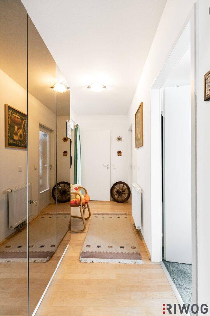 Langer Flur mit Spiegelschränken, Holzboden und heller Beleuchtung.