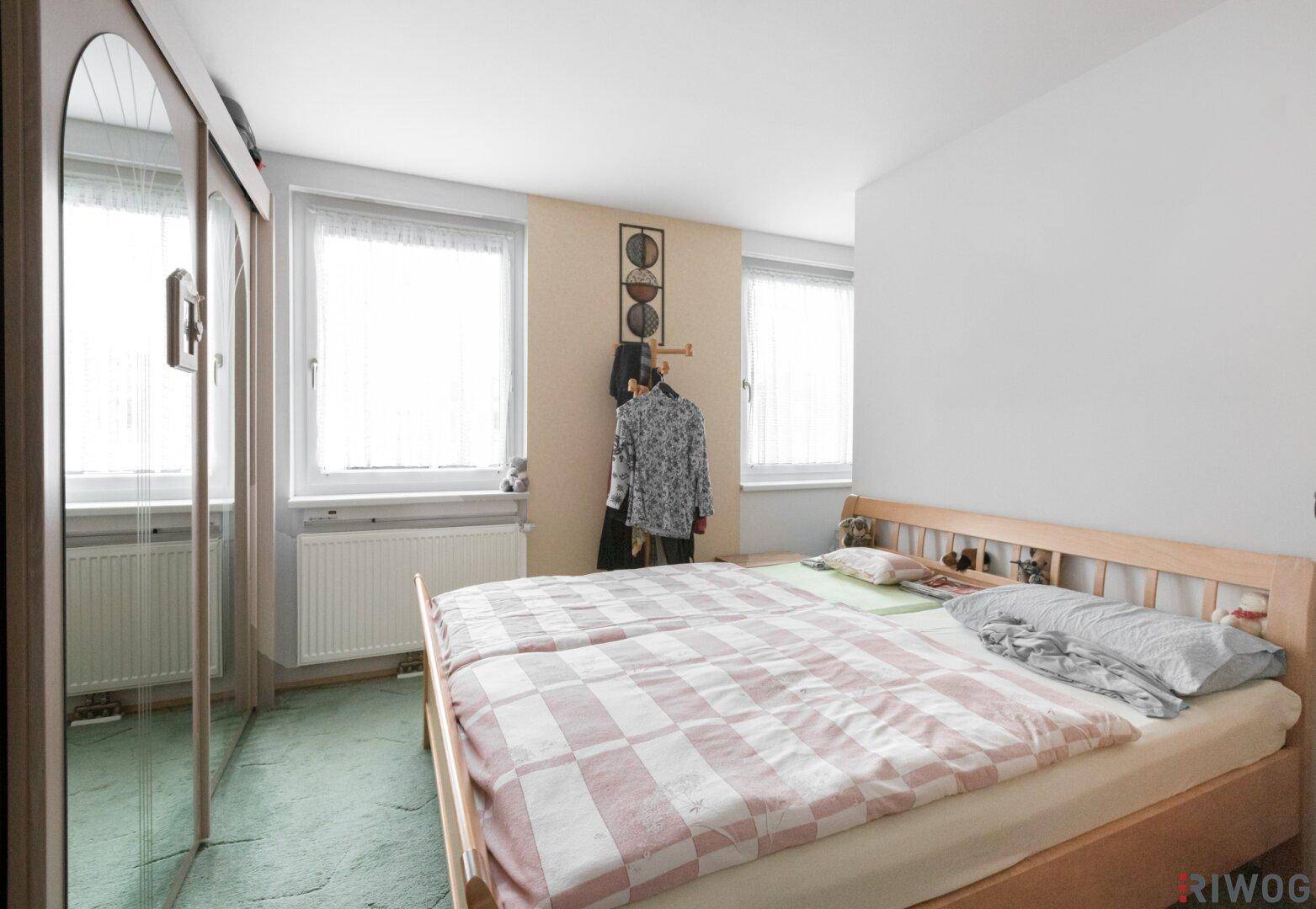Schlafzimmer mit Doppelbett, Teppichboden und Spiegelschränken für viel Stauraum.