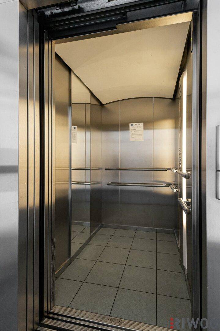 Innenansicht eines modernen Aufzugs mit Edelstahloberflächen und Spiegeln.
