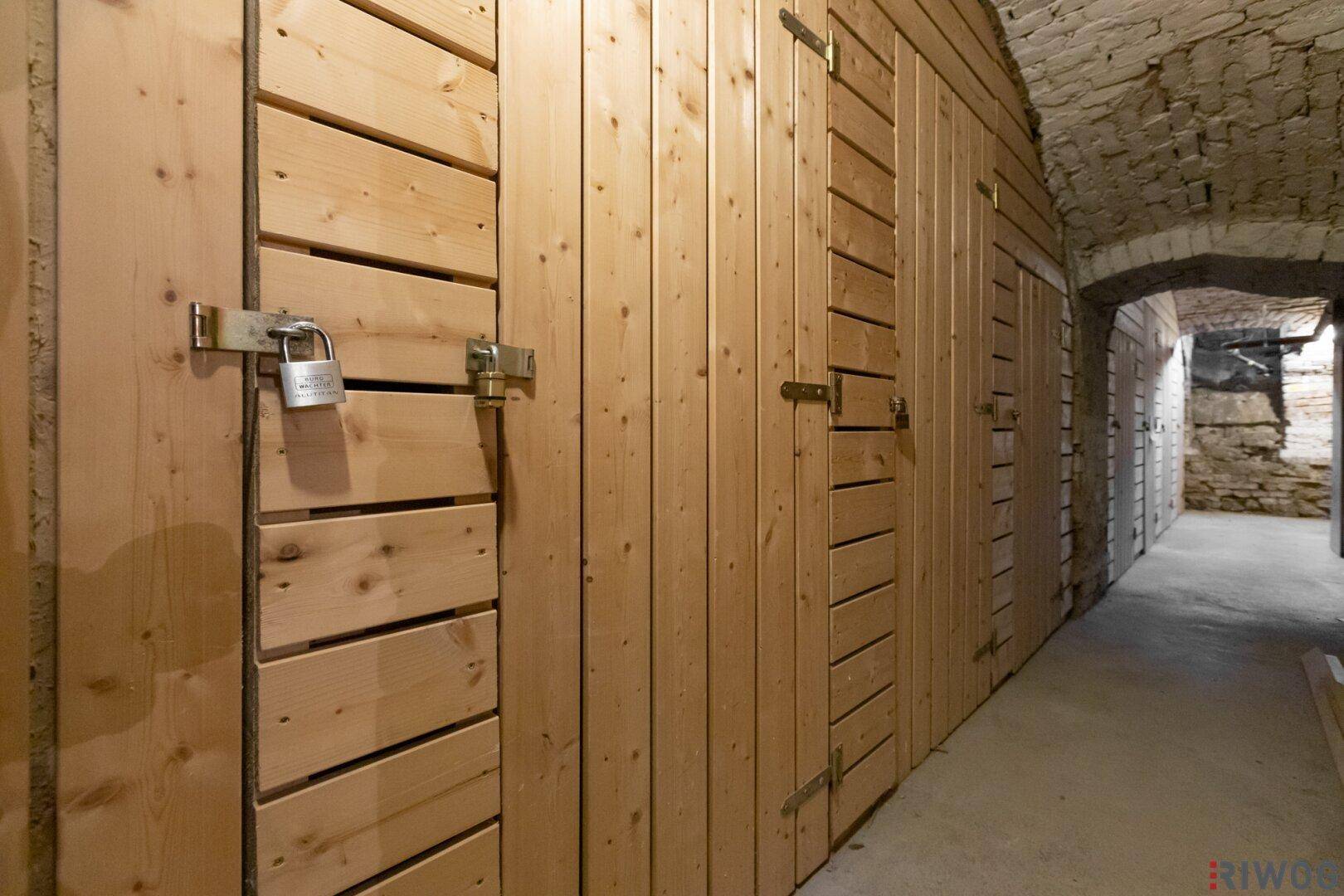 Kellerabteile mit Holztüren und gemauerten Wänden in einem historischen Kellergewölbe.